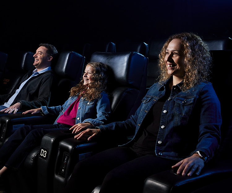 Famille visionnant un film en cinéma dans des sièges D-BOX